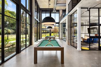 a pool table in the middle of a room with glass walls